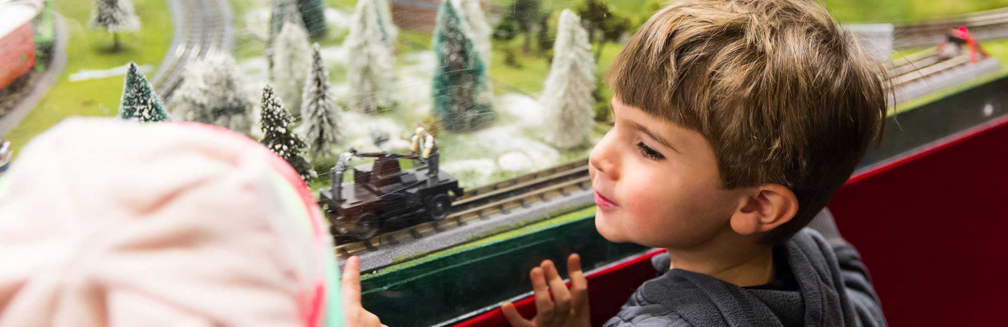 child looks in wonder at toy trains